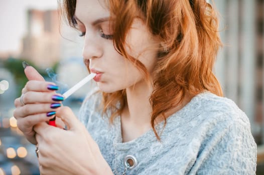 girl with a cigarette. young beautiful girl smokes a cigarette on the street. ignites the lighter, lighting his tobacco