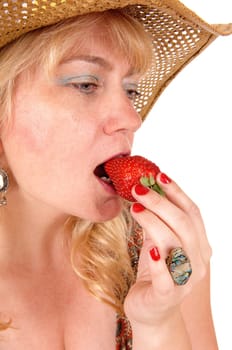 A beautiful close-up image of a blond woman with a straw hat eating.a big strawberry, isolated for white background..
