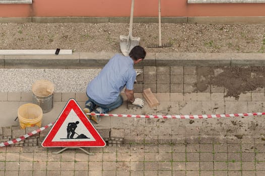 Bricklayer at work laying stone blocks of pavement.
