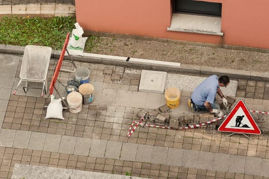 Bricklayer at work laying stone blocks of pavement.