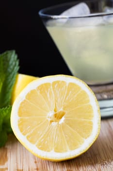 Fresh lemon half in front of lemonade or lemon cocktail