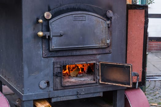 Indoor fireplace in a corner with firewood and axe in an old country house..