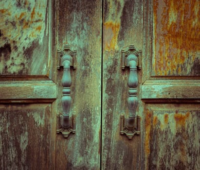 Grunge wooden door with metal handles. Vintage filter effect image.