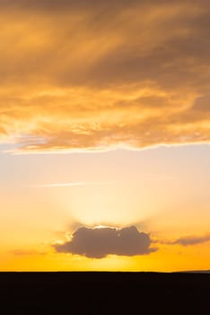 beautiful orange sunset with a sun behind a single cloud