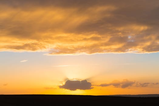 beautiful orange sunset with a sun behind a single cloud