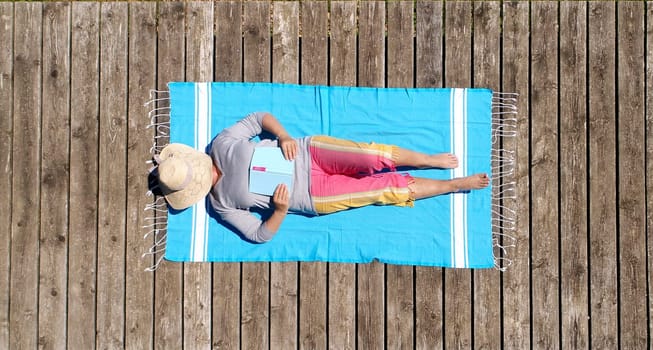 Drone recording - Senior citizen with book at the jetty at the lake