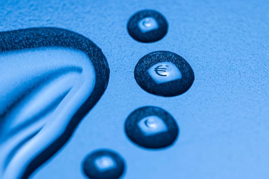 One larger cut liquid drop and several smaller ones with mirrored EURO symbol on blue background.