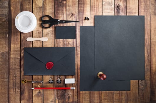 Photo of blank black stationery set on vintage wooden table background. Template for placing your design. Mockup for branding identity. Top view.