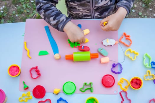 cute little boy playing with plasticine in the garden
