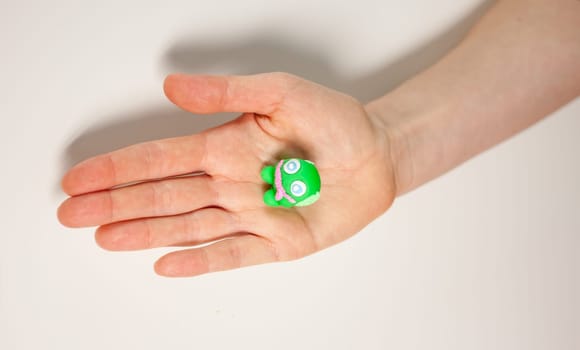 female hand showing small green monster made of plasticine