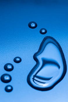 A running large liquid drop and several smaller drops with mirrored EURO symbol on a blue background.