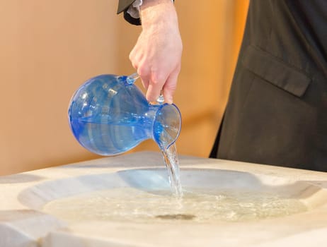 Pouring Water into Baptismal Font close up.