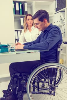 disabled businessman in wheelchair and his female colleague