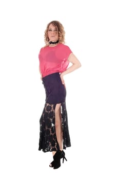 A beautiful young blond woman standing from the front in a pink.blouse and long black skirt, isolated for white background..