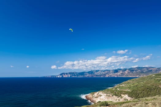 Colorful hang glider in sky over blue sea