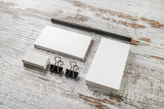 Business cards, pencil, eraser, badge and sharpener. Blank stationery on vintage wooden table background. ID template. Mockup for branding identity for designers.