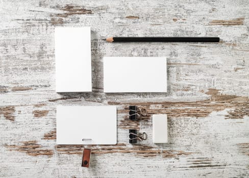 Photo of blank stationery. Business cards, badge, pencil and eraser on vintage wood table background. Responsive design mockup. Top view.