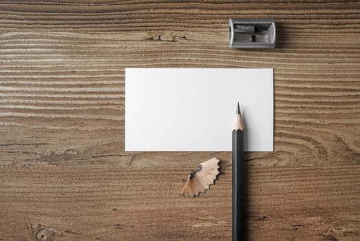 Photo of blank business card, pencil and sharpener on wooden table background. Responsive design mockup. Top view.