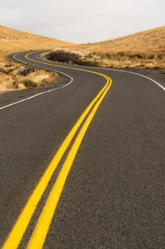 A well preserved two lane road leads around a bend to an interesting sky