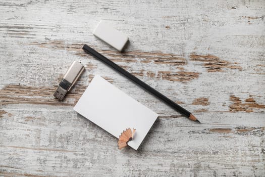 Photo of blank stationery. Bank business card, pencil, eraser and flash drive on vintage wooden table background. Top view.
