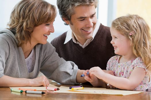 Parents helping their daughter draw