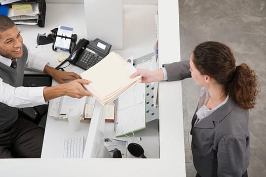 Man passing file to colleague