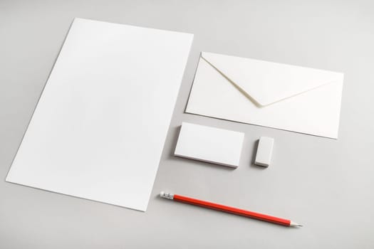 Photo of blank stationery set on paper background. Corporate identity template for placing your design. Blank letterhead, business cards, envelope, eraser and pencil. Top view.