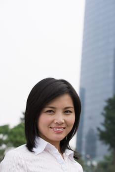 Smiling Chinese woman near skyscrapers
