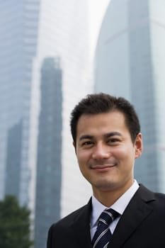 Smiling businessman near skyscrapers
