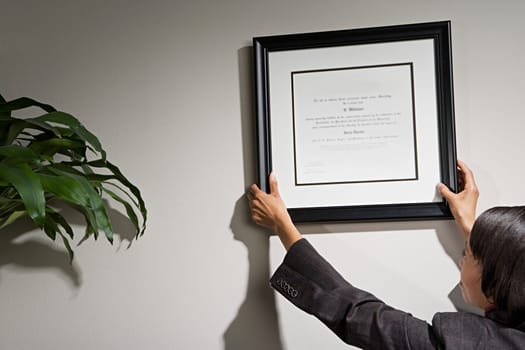 Business woman hanging framed certificate
