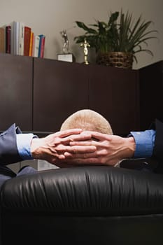 Businessman relaxing with hands behind his head