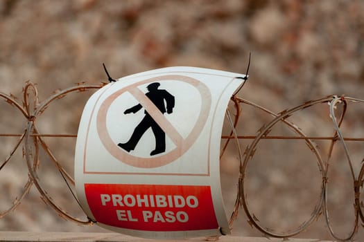 The image features a 'No Entry' sign mounted on a barbed wire fence, symbolizing restricted access and highlighting safety concerns in certain areas.