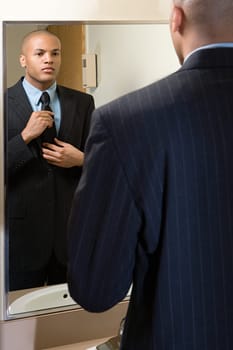 Man adjusting his tie in mirror