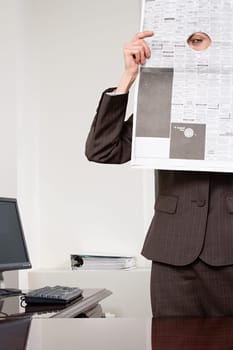 Woman looking through hole in newspaper