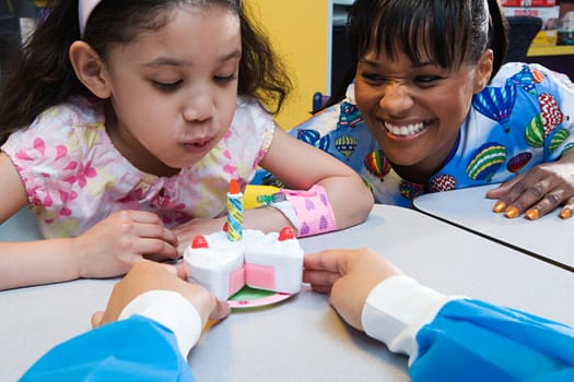 Girl and nurses with toy birthday cake