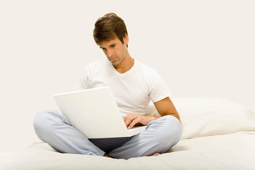 Man sitting on bed using laptop