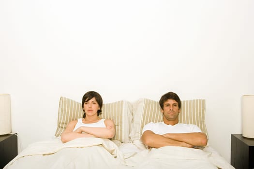 Couple in bed ignoring each other