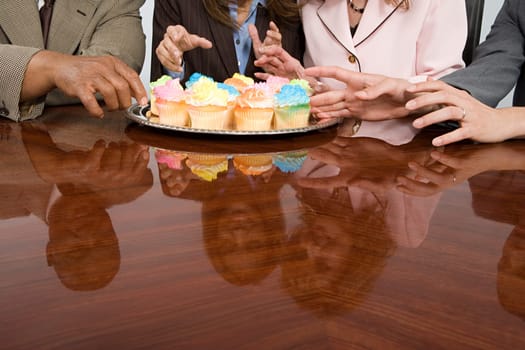 Businesspeople reaching for cupcakes