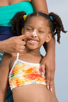 Mother putting suncream on daughters nose