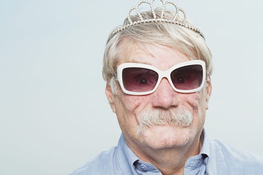 Senior man wearing a tiara and sunglasses