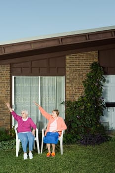 Two senior women sat in garden waving
