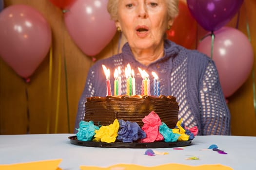 Senior woman blowing out candles on cake