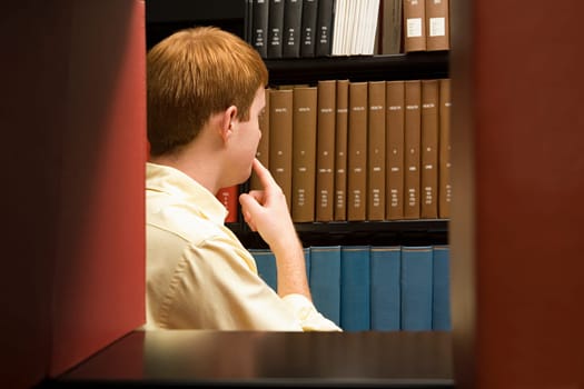 Male student choosing a book in the library