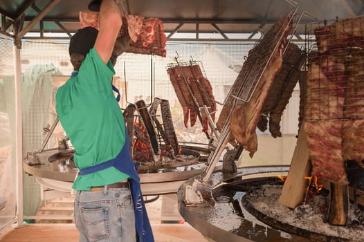 Cook prepares the meat to roast on the grill. Argentine asado.