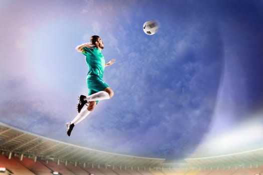 Athlete heading soccer ball in stadium