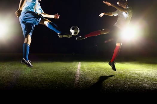 Two soccer players kicking a soccer ball