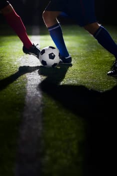 Two soccer players kicking a soccer ball