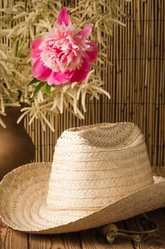 Straw hat and peony flower, close-up