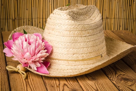 Straw hat and peony flower, close-up