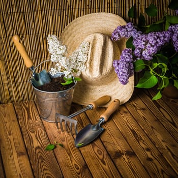 Gardening tools and a branch of a blossoming white lilac on a wooden surface